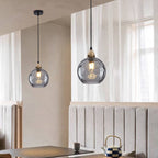 Smoke gray Clérachic water ripple glass globe pendants in a dining nook, the dimpled glass reading softly translucent.