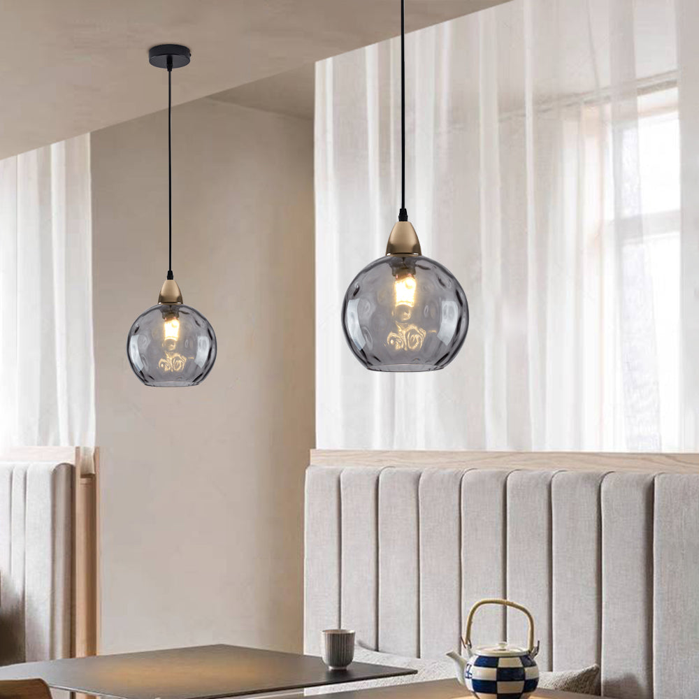 Smoke gray Clérachic water ripple glass globe pendants in a dining nook, the dimpled glass reading softly translucent.