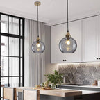 Two smoke gray Clérachic water ripple glass globe pendants over a white kitchen island, the bulb visible through the tinted glass.
