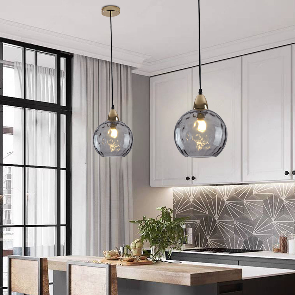 Two smoke gray Clérachic water ripple glass globe pendants over a white kitchen island, the bulb visible through the tinted glass.
