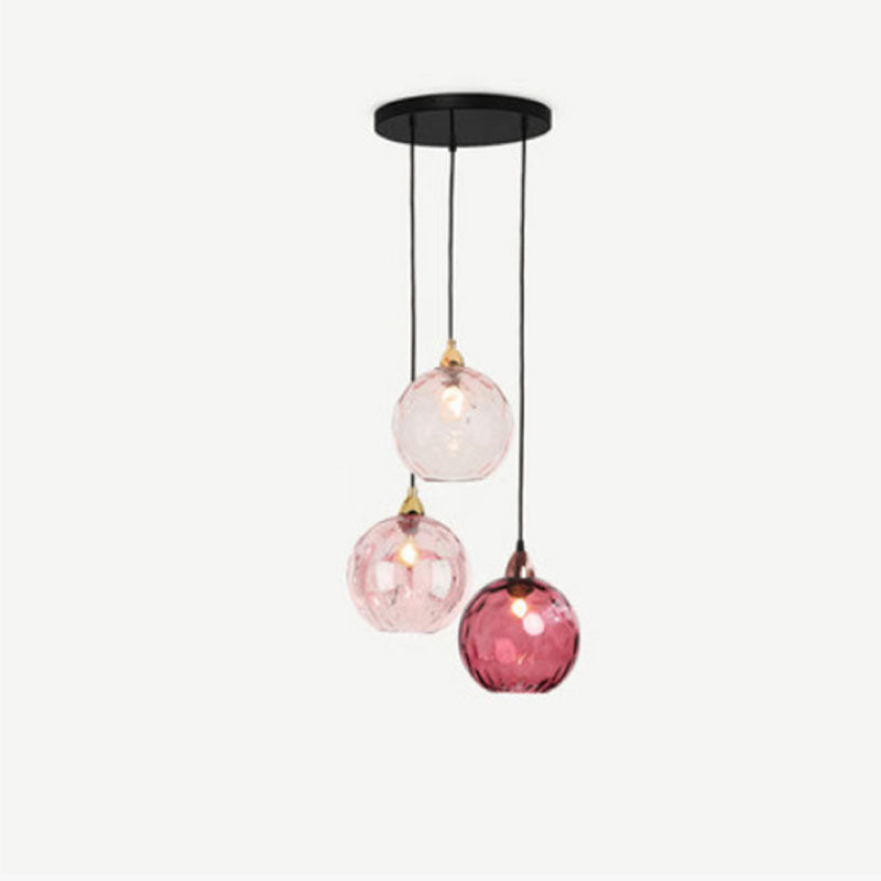Clérachic Water-Ripple Glass Pendant Light in pink, three globes staggered from a round black canopy on a plain backdrop.