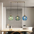 Clérachic Water-Ripple Glass Pendant Light in green and blue, three level globes lighting a long wooden dining table.