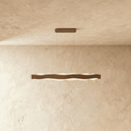 Clérachic linear wavy LED pendant in a bronze-toned finish, hung on two fine cables with an oblong ceiling plate.