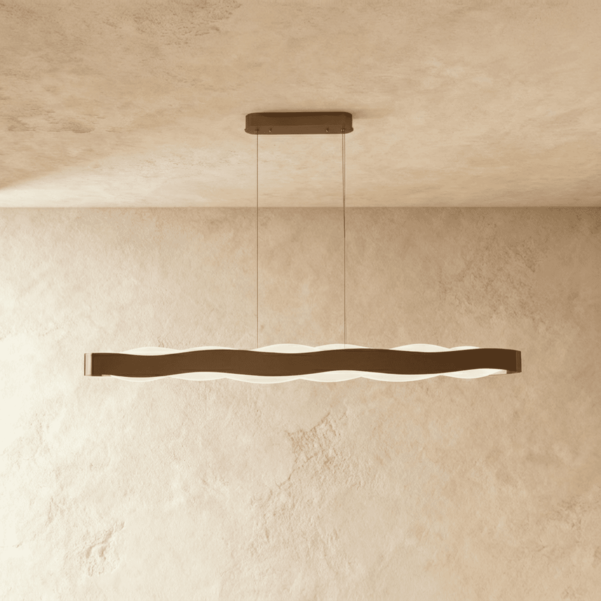 Clérachic longer linear wave pendant in a bronze-toned finish, its frosted light glowing under the wavy band.