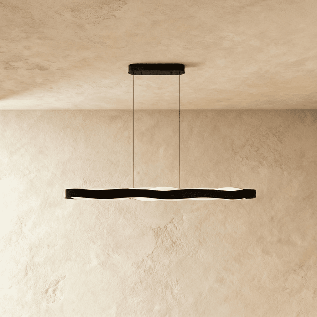 Clérachic black linear wave pendant on two thin cables, its soft frosted LED glow visible below the band.