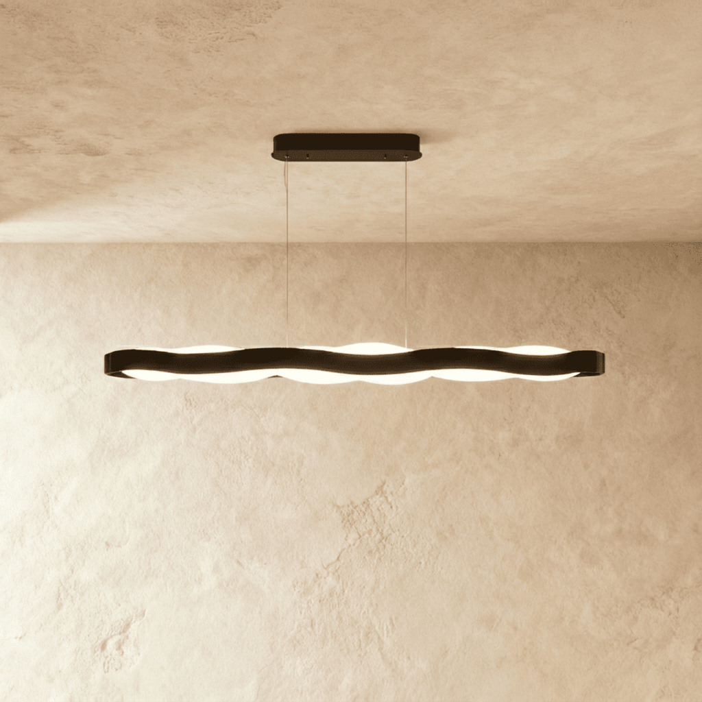 Clérachic long black wavy LED pendant with an oblong black ceiling plate, lit against a limewash wall.