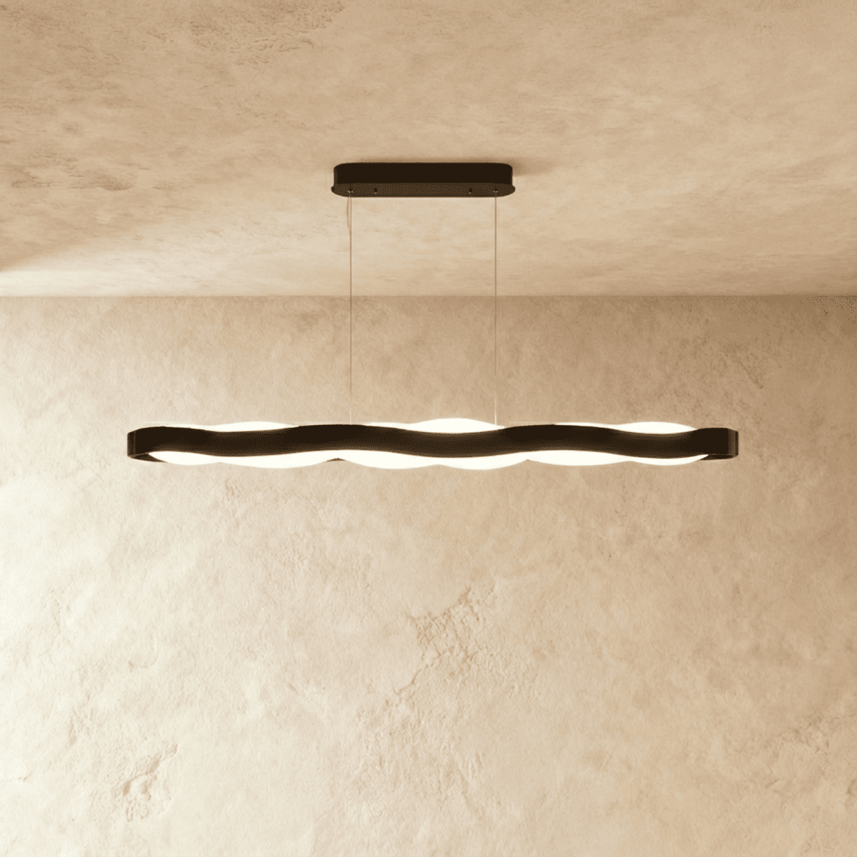 Clérachic long black wavy LED pendant with an oblong black ceiling plate, lit against a limewash wall.