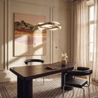 Clérachic gold wave-ring chandelier above a dark wooden desk in a panelled room with a landscape painting.
