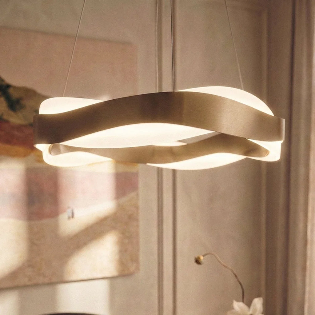 Close view of the Clérachic gold wave-ring chandelier, brushed metal bands crossing over a glowing frosted diffuser.