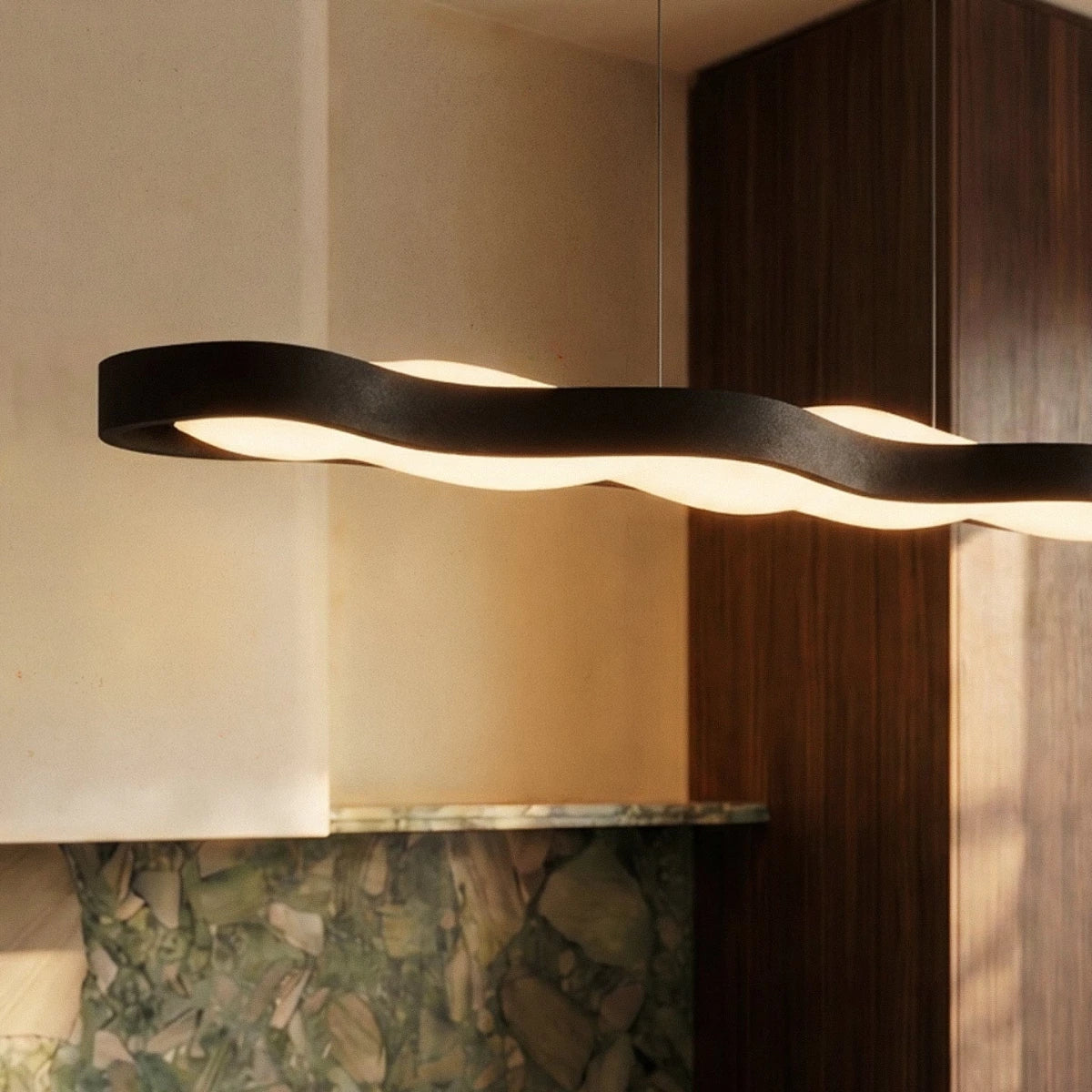 Close view of the Clérachic black linear wave pendant, a textured black band over warm frosted LED light.
