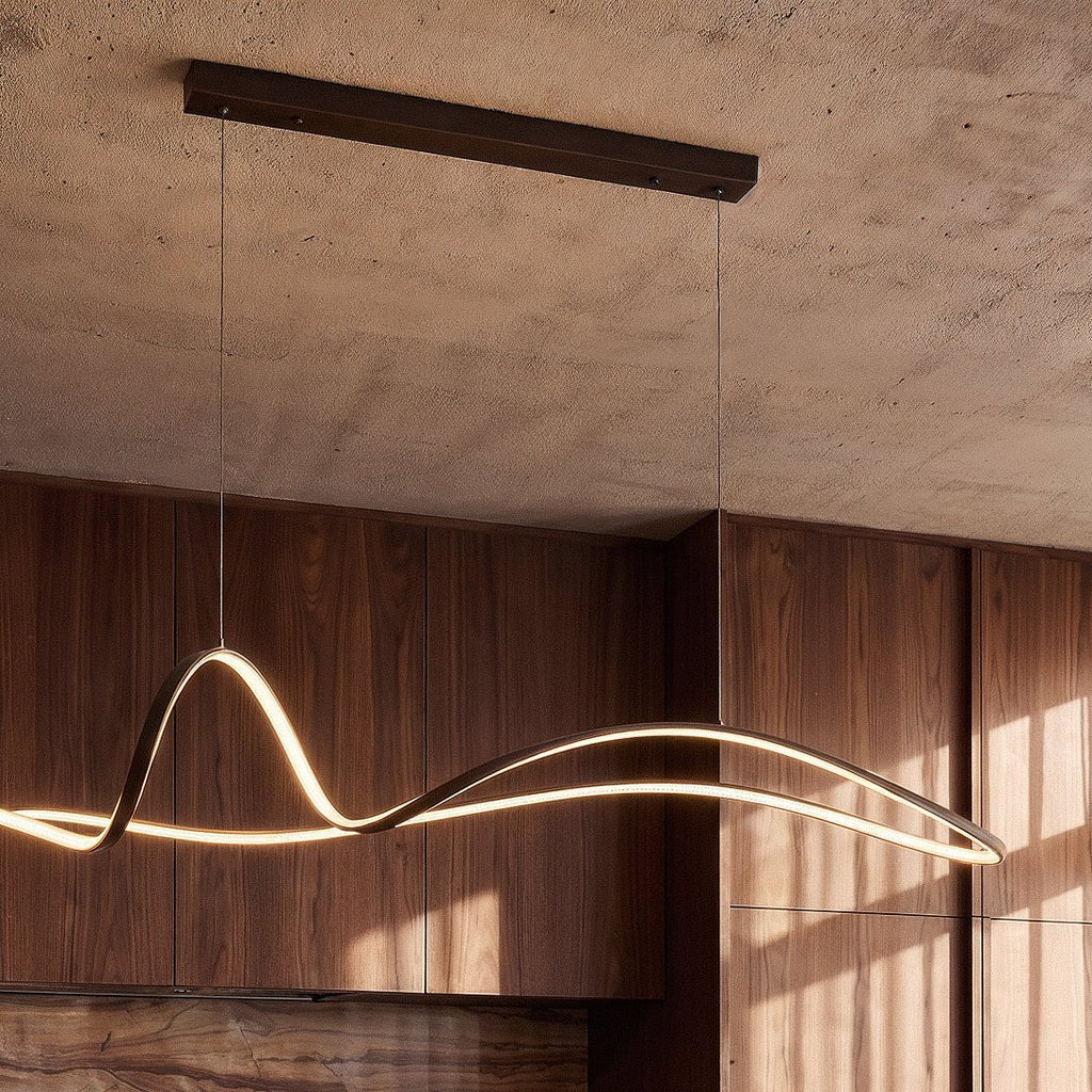 Close view of the Clérachic black ribbon pendant, its LED edge lit warm, under a long bar canopy on a concrete ceiling.