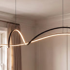 Close view of the Clérachic black ribbon pendant curving and twisting, its slim LED edge lit against panelled walls.
