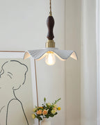 This Clérachic pendant hangs in front of a line-drawing portrait and a posy of yellow flowers, with a dark wooden handle above the brass cap.