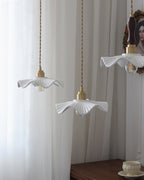 Three of this Clérachic pendant's wavy ceramic shades hang at different heights in front of white curtains.