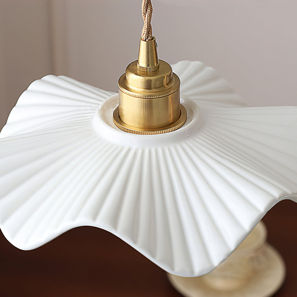 Close view of the ribbed white ceramic shade with its wavy edge, below the brass cap, on this Clérachic pendant.