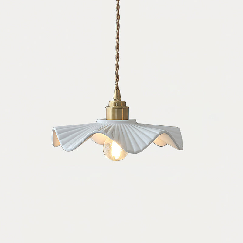 Short Clérachic pendant with a pleated white ceramic shade, a brass cap and a lit filament bulb, against a pale background.