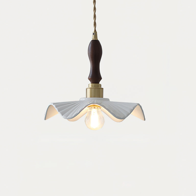 This Clérachic pendant glows softly, with a dark wooden handle above the brass socket and a rippled white shade, on a pale backdrop.