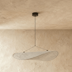 Clérachic leaf-shaped pendant in an unlit white woven-look shade on thin wires and a black ceiling rose, against limewash plaster walls.