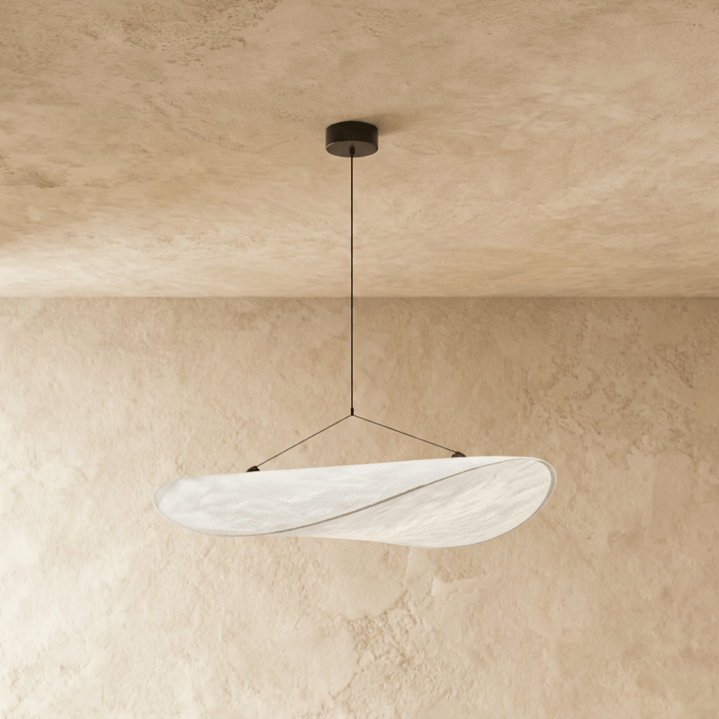 Clérachic twisted white pendant shade glowing softly, hung from a black ceiling rose against a warm limewash plaster wall.