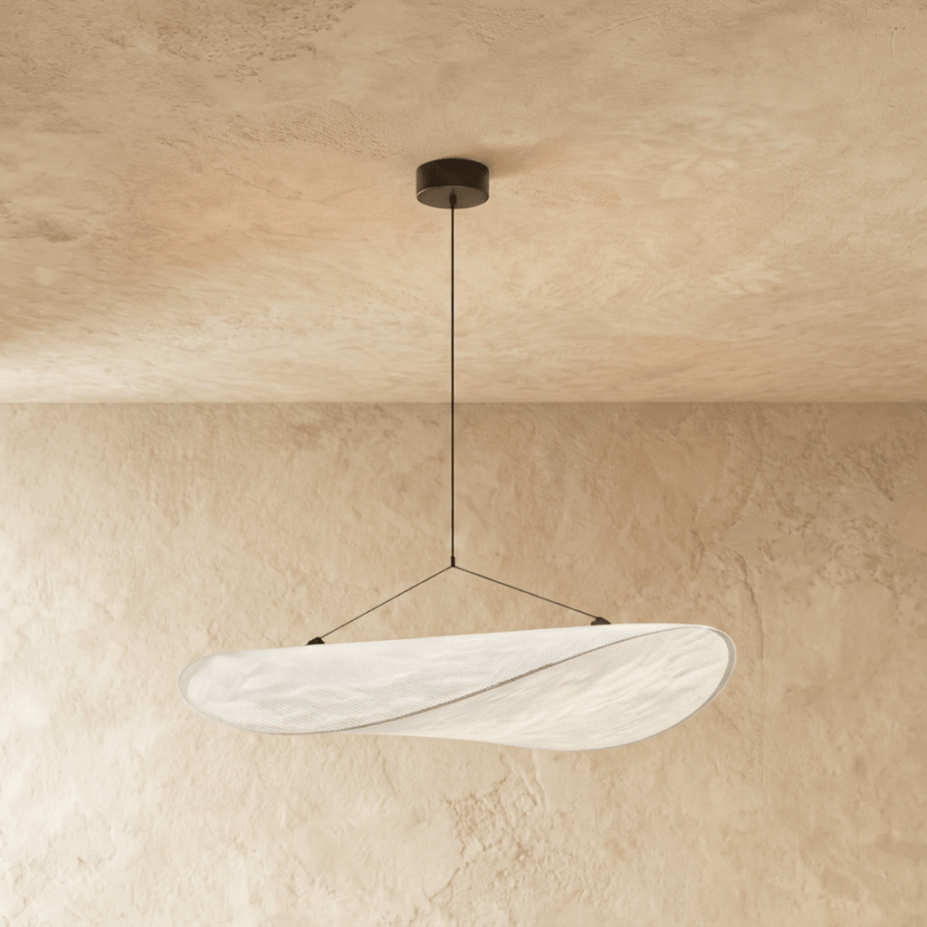 Clérachic wide white pendant with a curved, folded shade and a fine seam, hung from a black canopy on a plaster wall.
