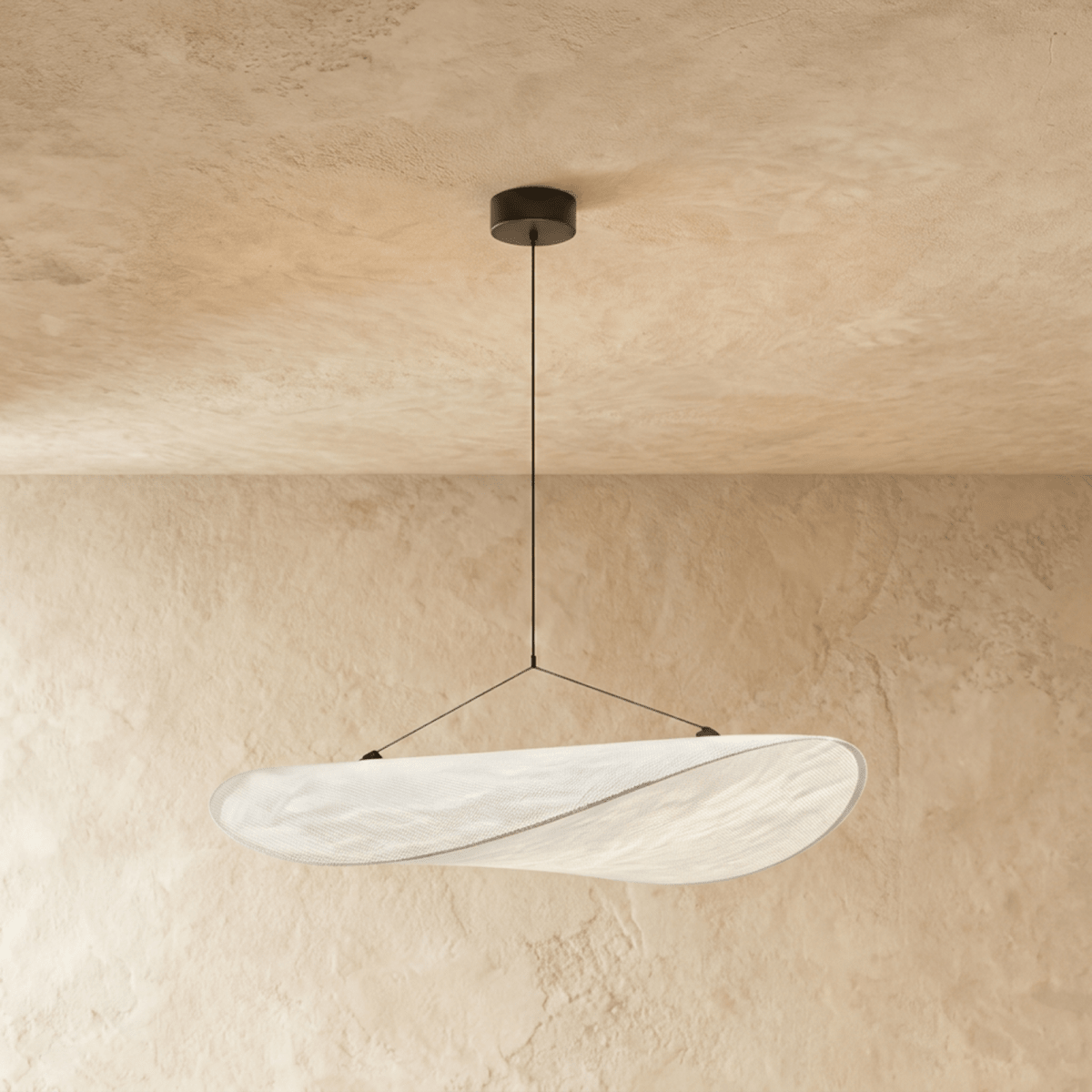 Clérachic wide white pendant with a curved, folded shade and a fine seam, hung from a black canopy on a plaster wall.