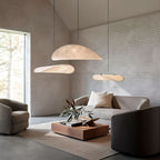 Clérachic three white pendants glowing at different heights in a high-ceilinged room with white brick walls and a low sofa.