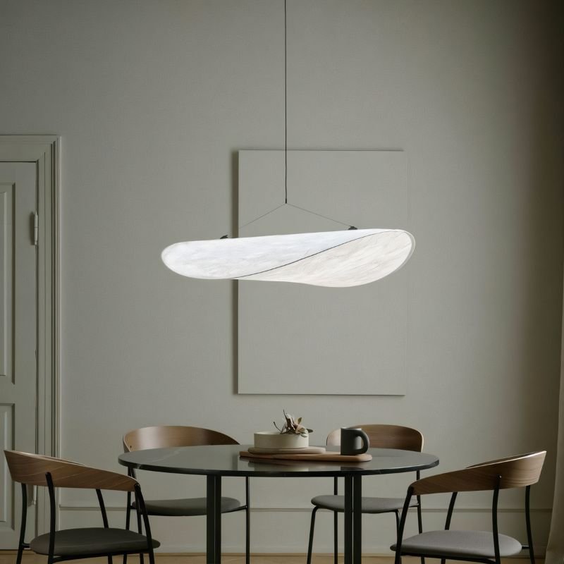 Clérachic white leaf-shaped pendant lit over a round dark dining table with wooden chairs, in a muted grey-green room.