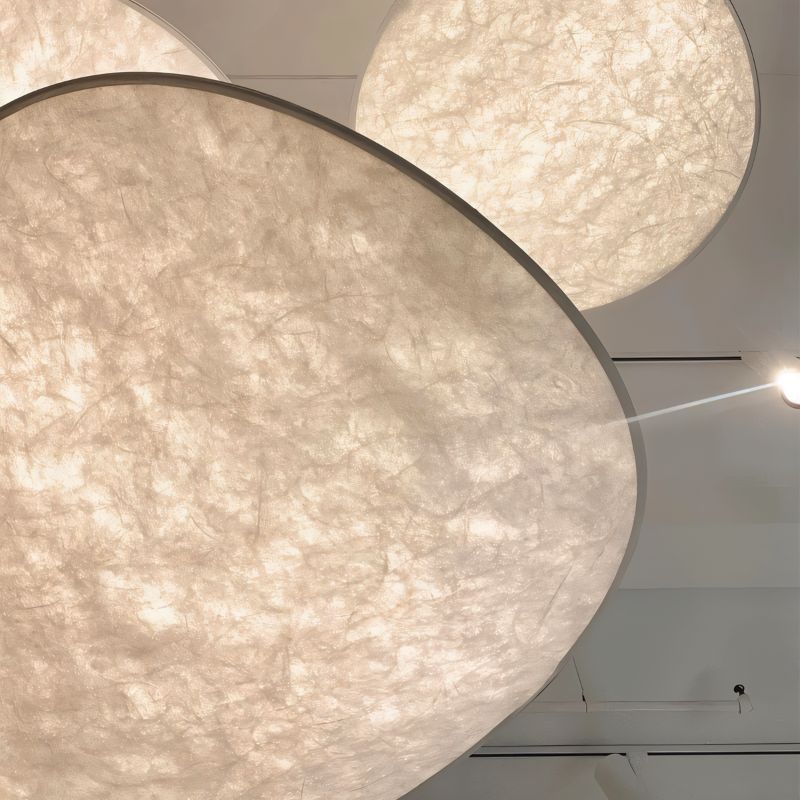 Clérachic white fibrous pendants seen from below, their translucent shades glowing warm against a white ceiling.