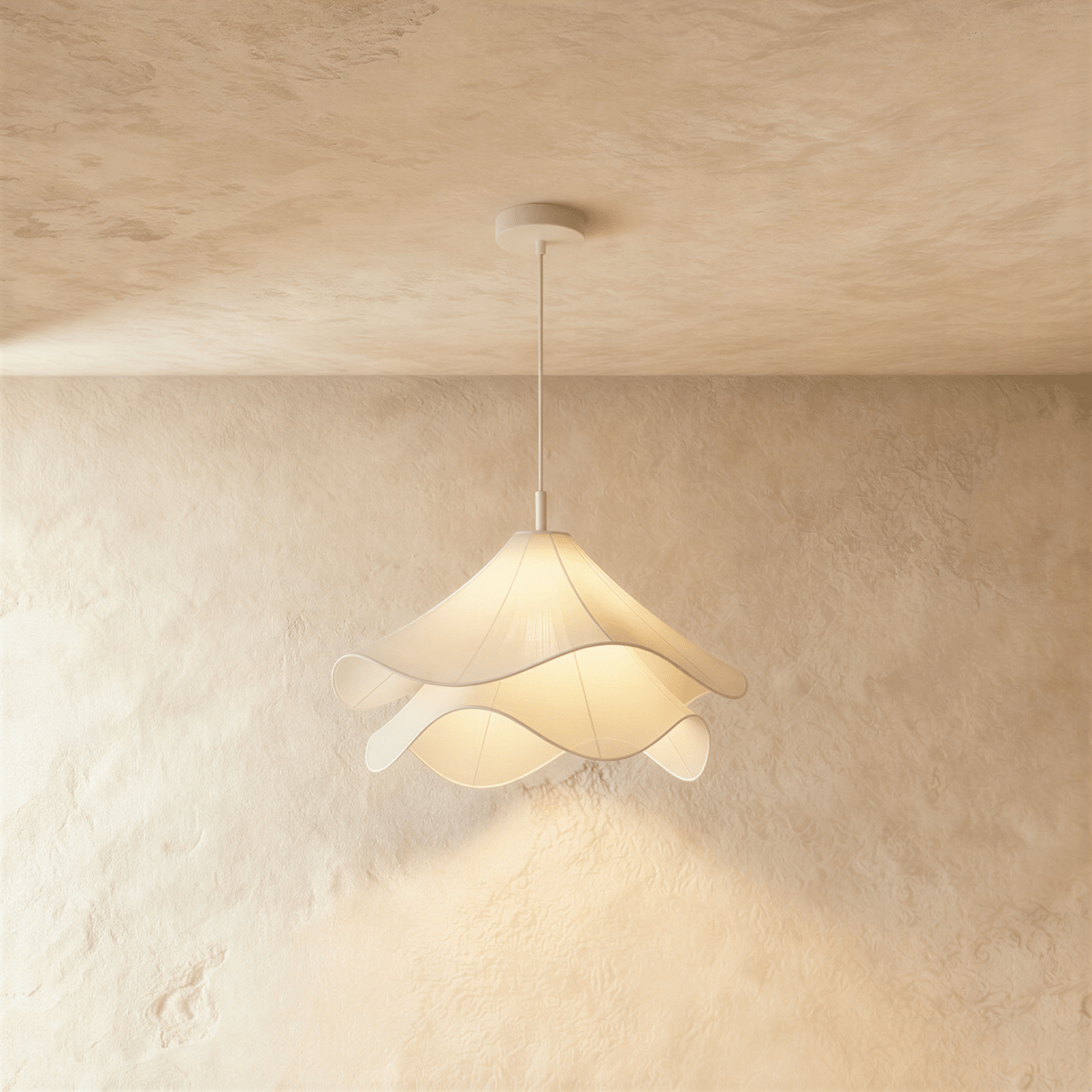 Clérachic pendant with soft rippled white fabric layers glowing warmly, hung from a white canopy against plaster.