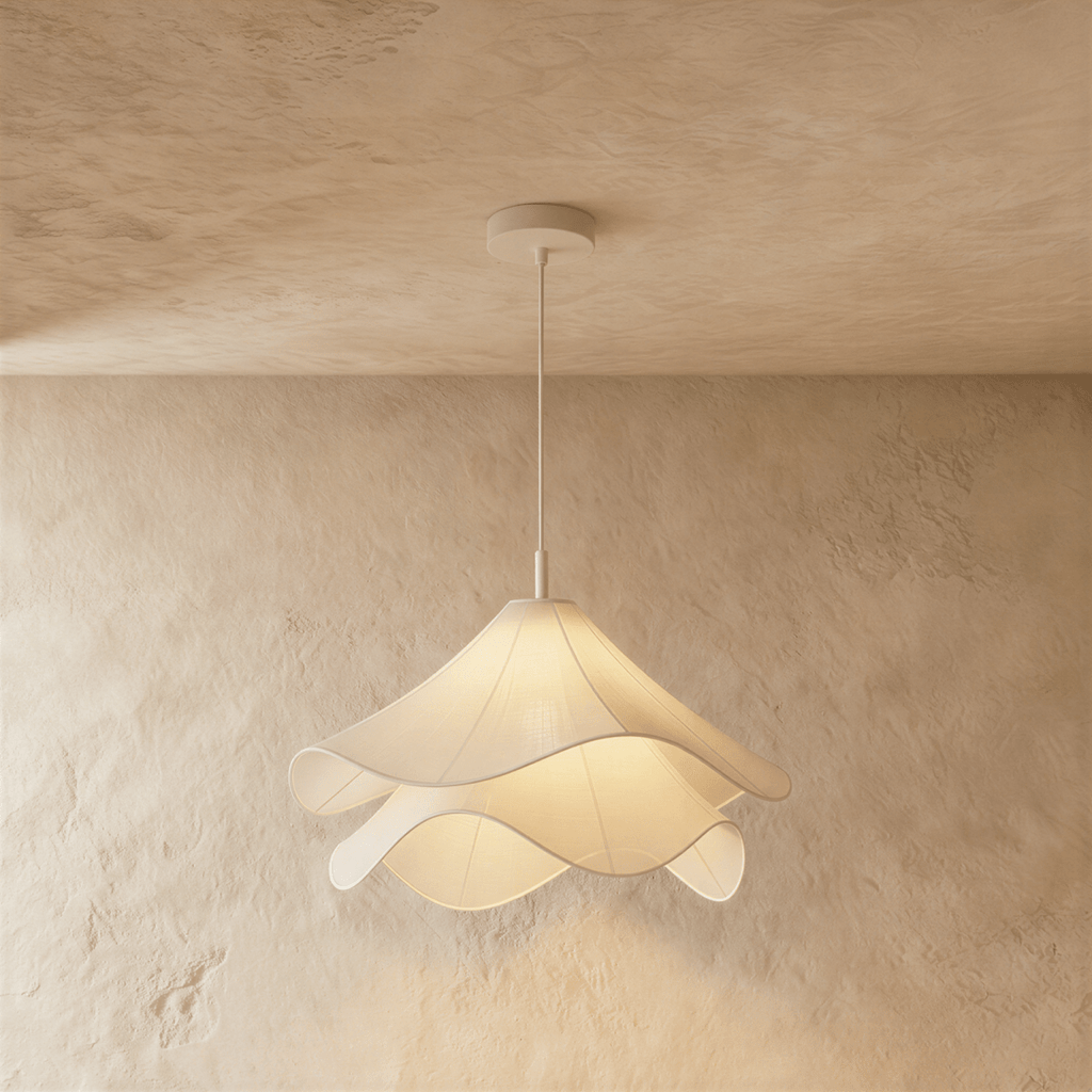 Clérachic layered white fabric pendant lit from within, its wavy edges casting a warm glow on a limewash wall.