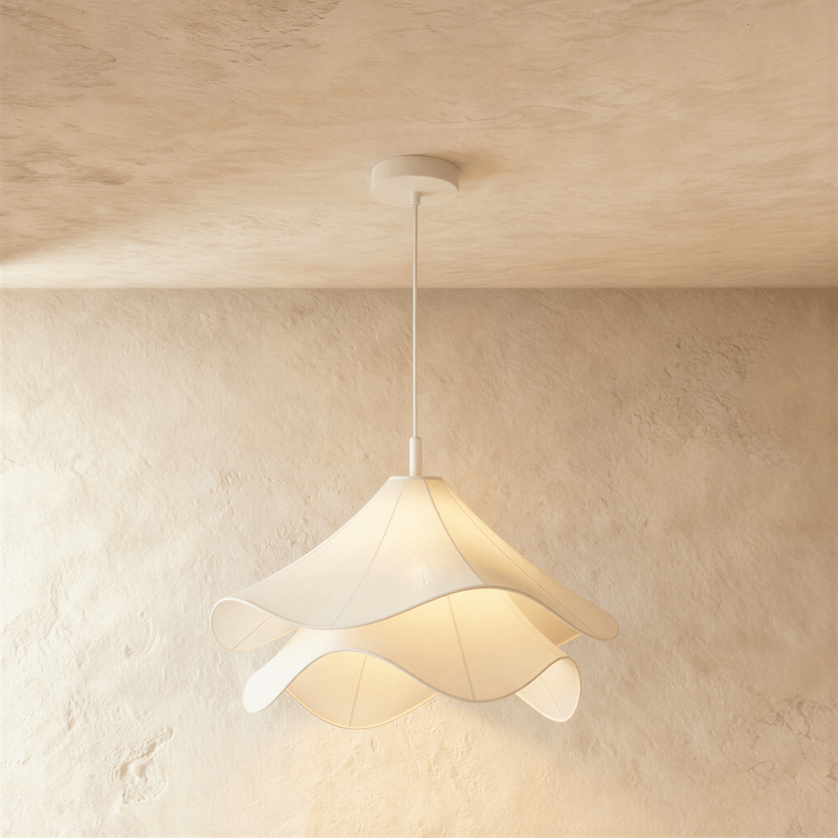 Clérachic wave-edged fabric pendant seen close up, two tiers of white cloth diffusing warm light below a white canopy.