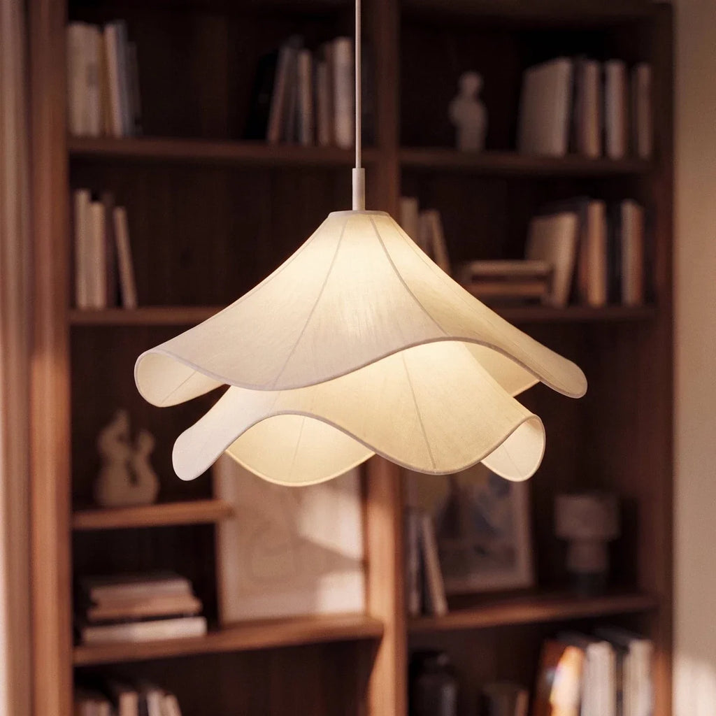 Clérachic pendant with layered white fabric glowing softly in front of a walnut bookcase filled with books.