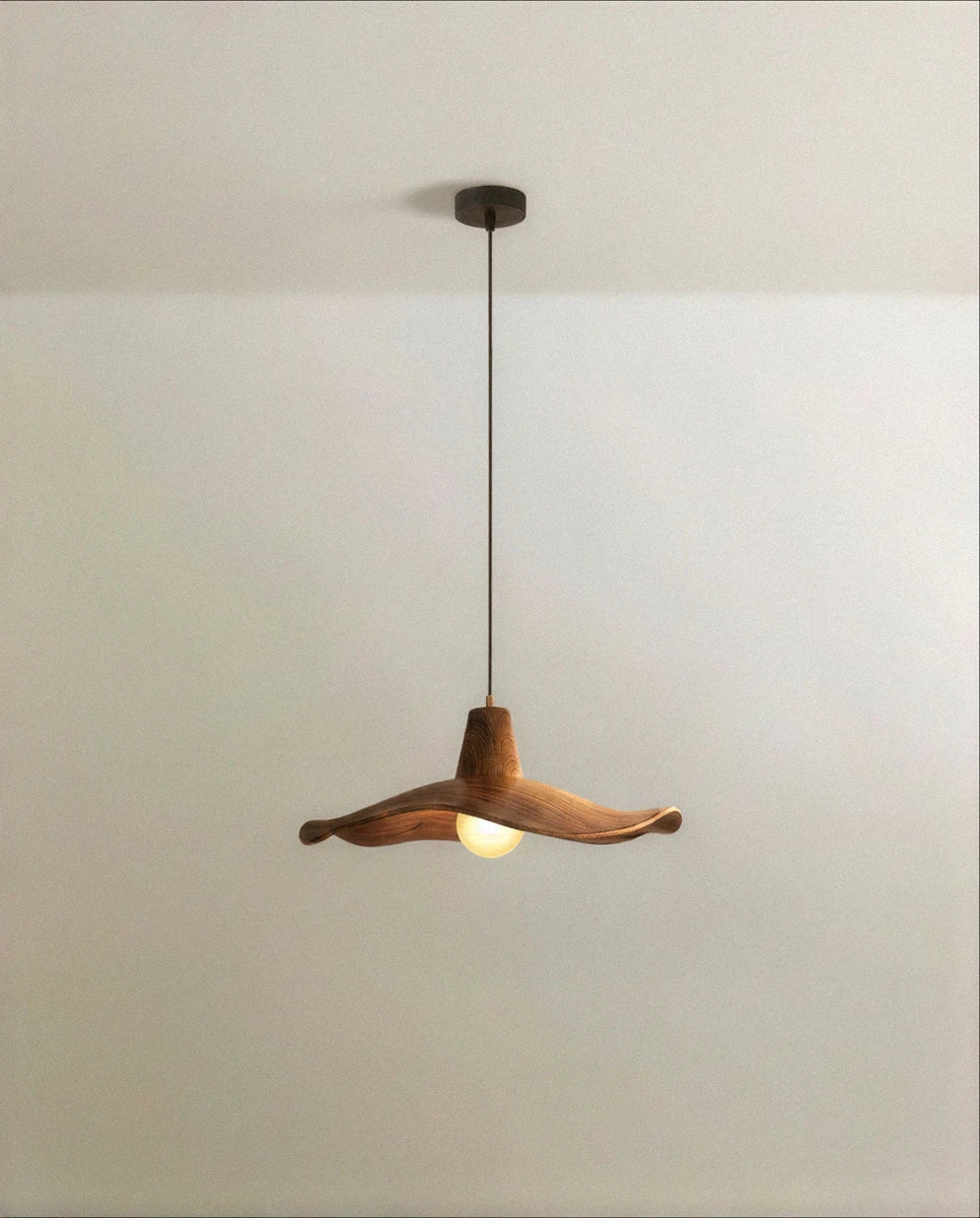 Clérachic pendant with a wavy, walnut-toned wooden shade on a slim dark cord, lit by a frosted globe bulb, studio shot.