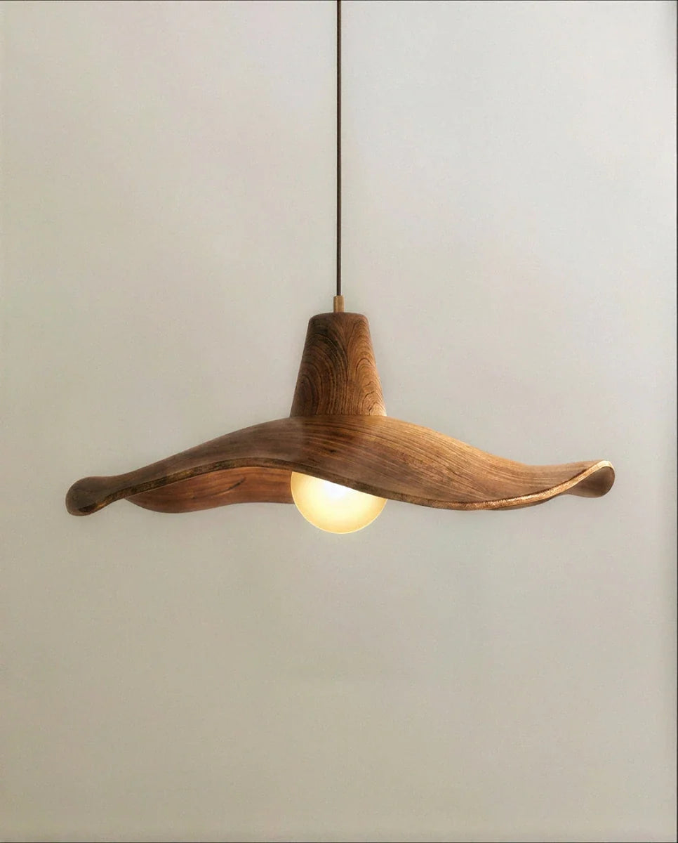 Clérachic wavy wooden pendant shade up close, with visible grain, a rippling rim and a warm frosted bulb glowing beneath.