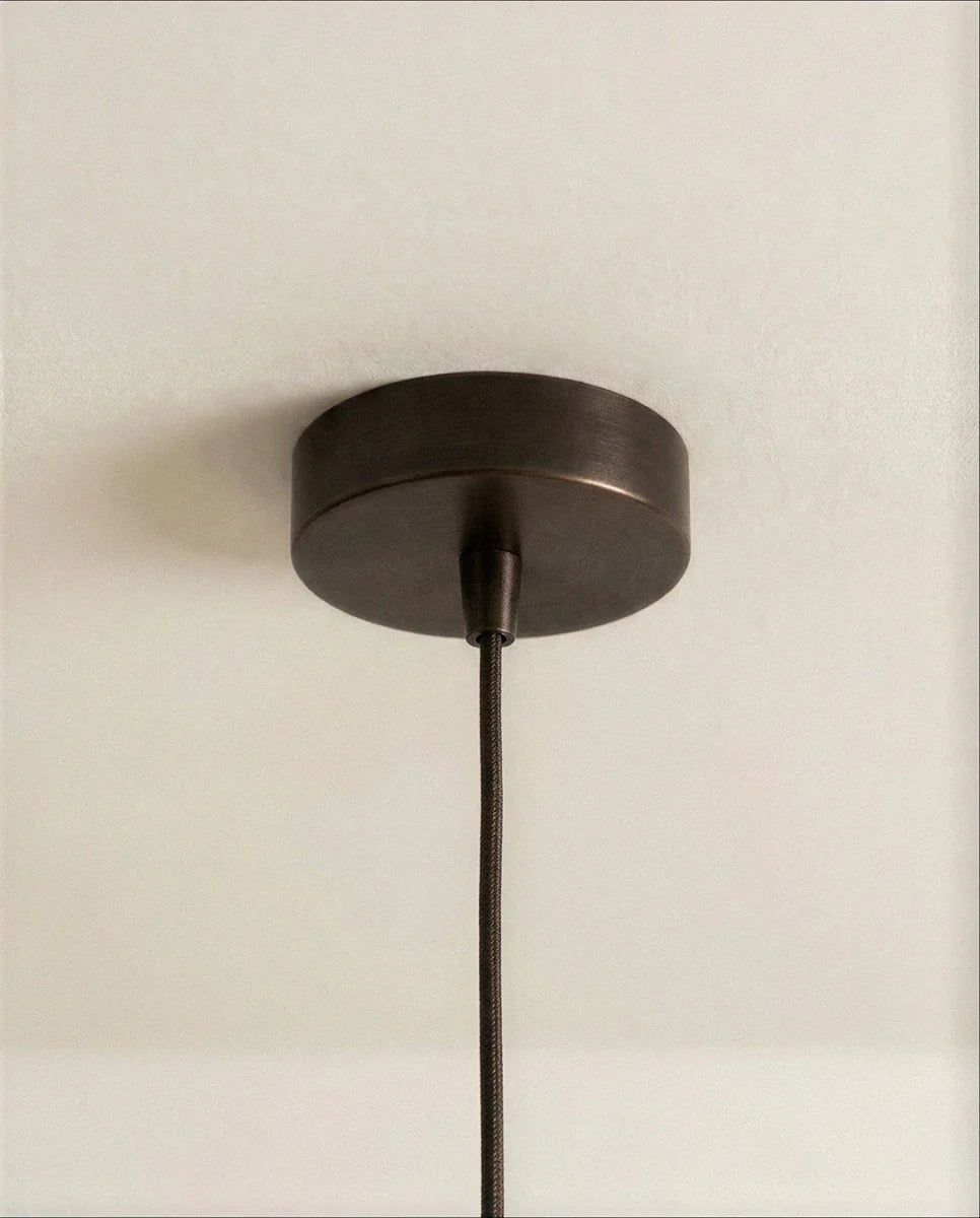 Clérachic pendant detail of the round dark bronze ceiling canopy and braided cord against a pale ceiling.