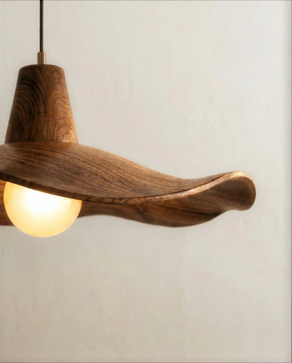Clérachic pendant close up showing the curled wooden rim, fine grain and the glowing frosted globe bulb under the shade.