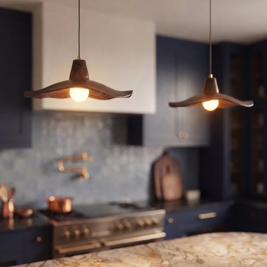 Clérachic wooden pendants softly blurred in the foreground of a kitchen room with navy cabinets and a gleaming pot filler.