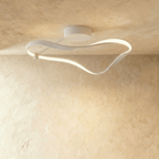 Clérachic mid-length white ribbon ceiling light with a soft diffused LED band and a round canopy, on a warm plaster ceiling.