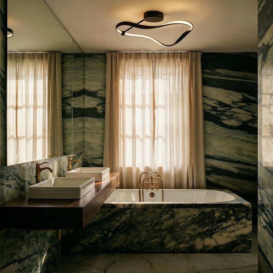 Clérachic black ribbon ceiling light lit above a bathroom with green marble walls, a stone bath, brass taps and linen curtains.