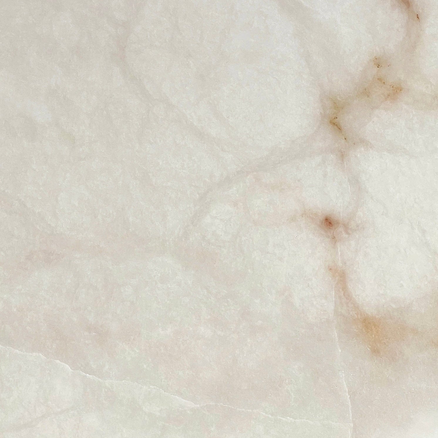 Close detail of the alabaster used on the Clérachic Weft sconce, warm russet veining running through pale stone.