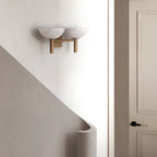 The Clérachic Weft sconce in brass mounted above a curved staircase, sitting flush against the plaster.
