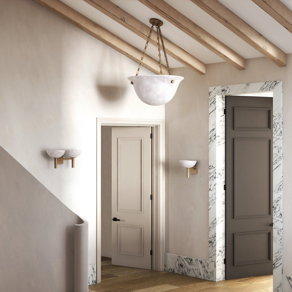 Clérachic Weft sconces in brass lining a beamed hallway, spaced along the wall beside marble-framed doorways.