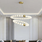 Close under a cove-lit ceiling, this Clérachic chandelier shows both globe rings with brass spheres between the beads.
