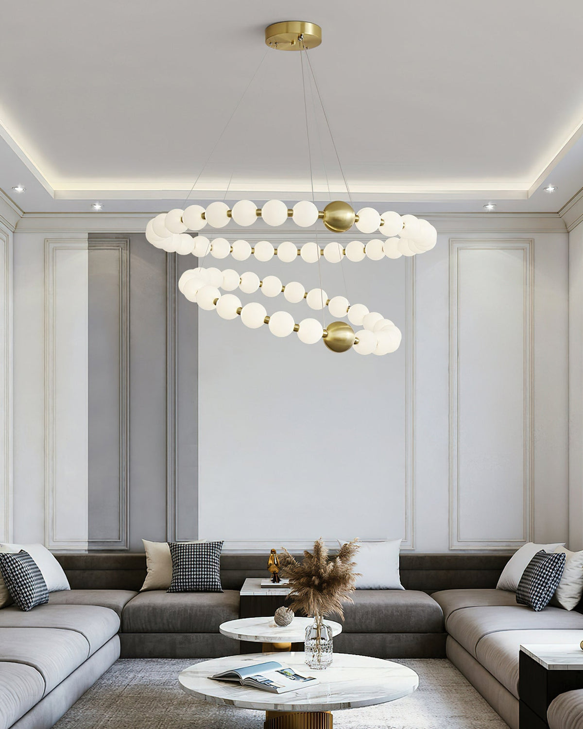 Wider view of a Clérachic chandelier with two globe rings, centred over a corner sofa and round marble coffee table.
