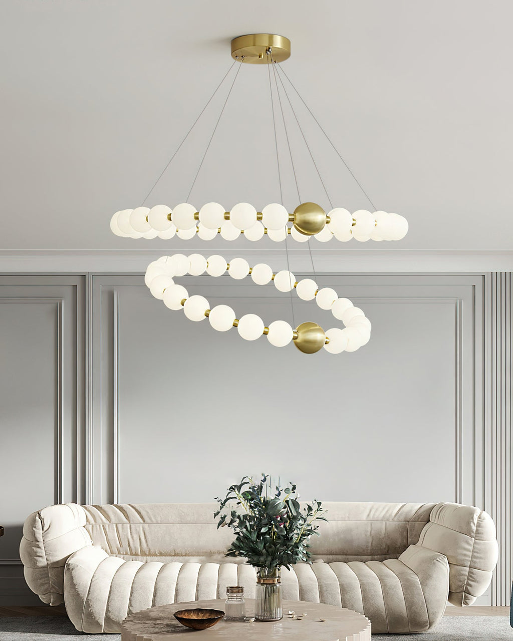 The two-ring Clérachic chandelier seen from slightly further back, with panelled grey walls and a sofa below.