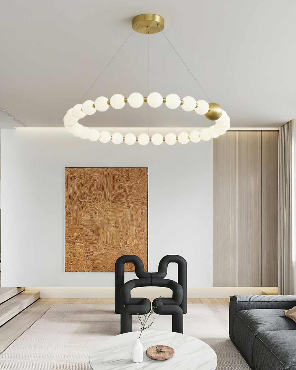A single-ring Clérachic chandelier of white globes hangs in a bright room with a sculptural black chair and a marble table.