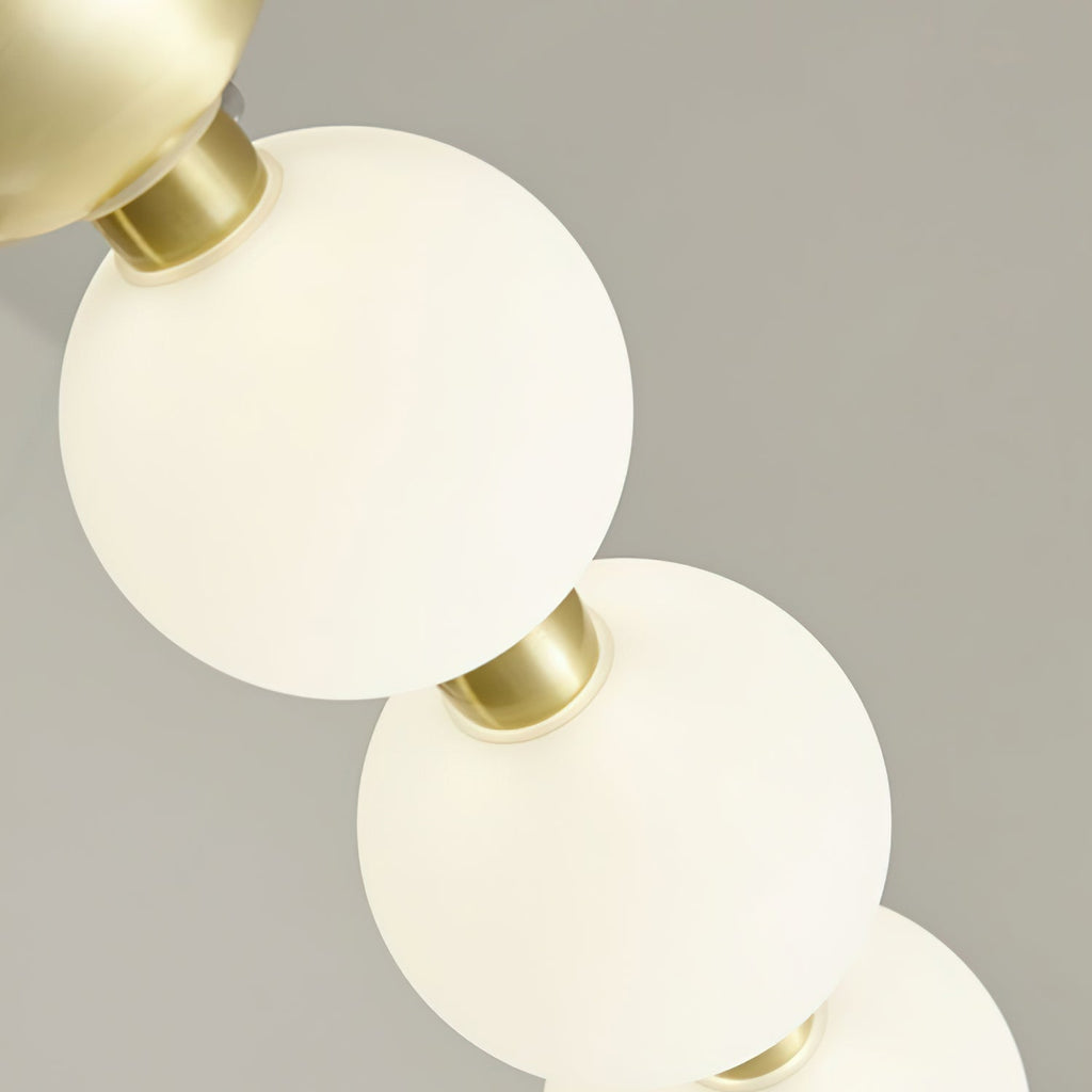 Close view of two lit globes glowing warm white on a brass collar, from this Clérachic chandelier.