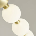 Close view of two lit globes glowing warm white on a brass collar, from this Clérachic chandelier.