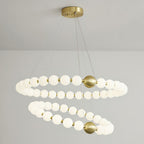 A two-ring Clérachic chandelier lit against a grey wall, with a round brass ceiling plate and fine suspension cables.
