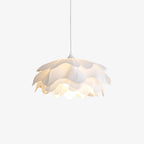 This Clérachic white pendant with layered petals, lit from within and hung on a thin white cord against a plain backdrop.
